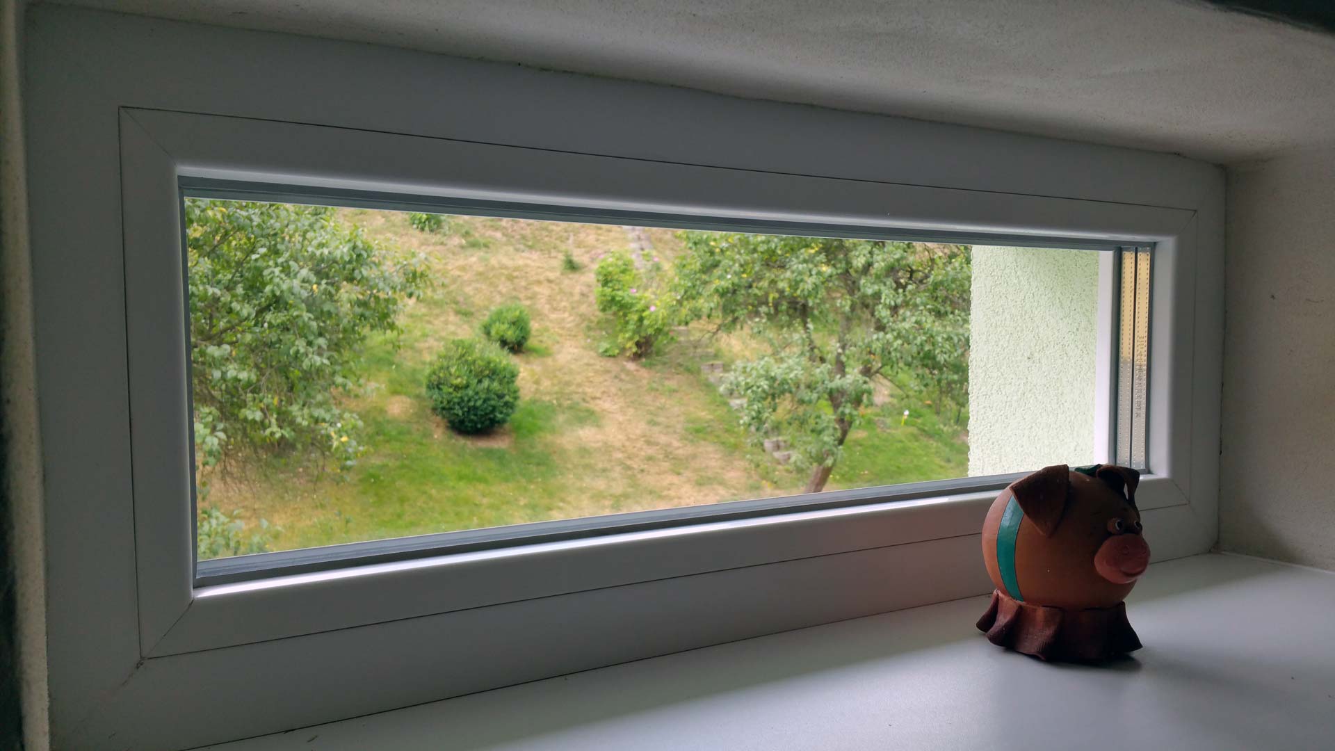 Úzké fixní okno na chodbě rodinného domu.